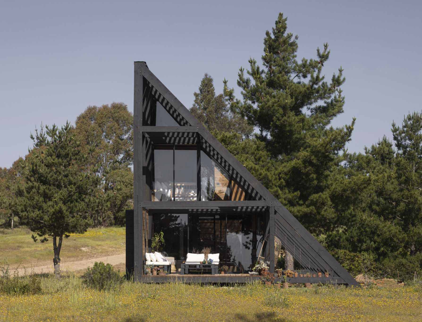 A small wedge-shaped home with a black exterior that's located on the windy beach of Matanzas, Chile.